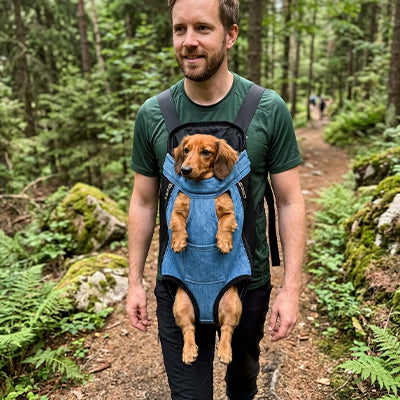 homme sentier foret teckel sac de transport chien bleu jeans porte devant