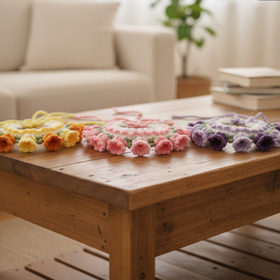 trois colliers pour chien crochet fleurs jaune rose violet poses sur table en bois